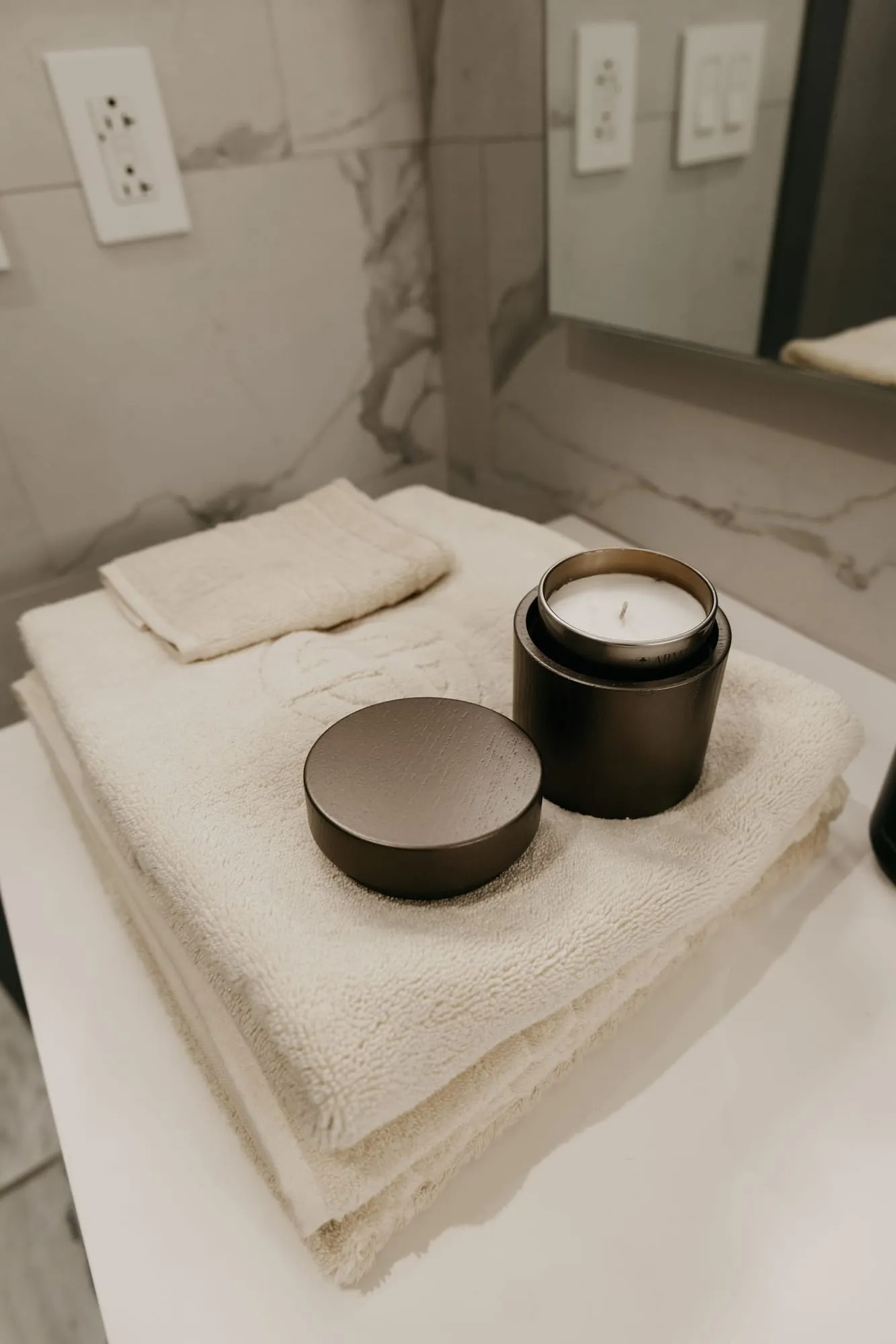 Candle and towels on a white spa counter