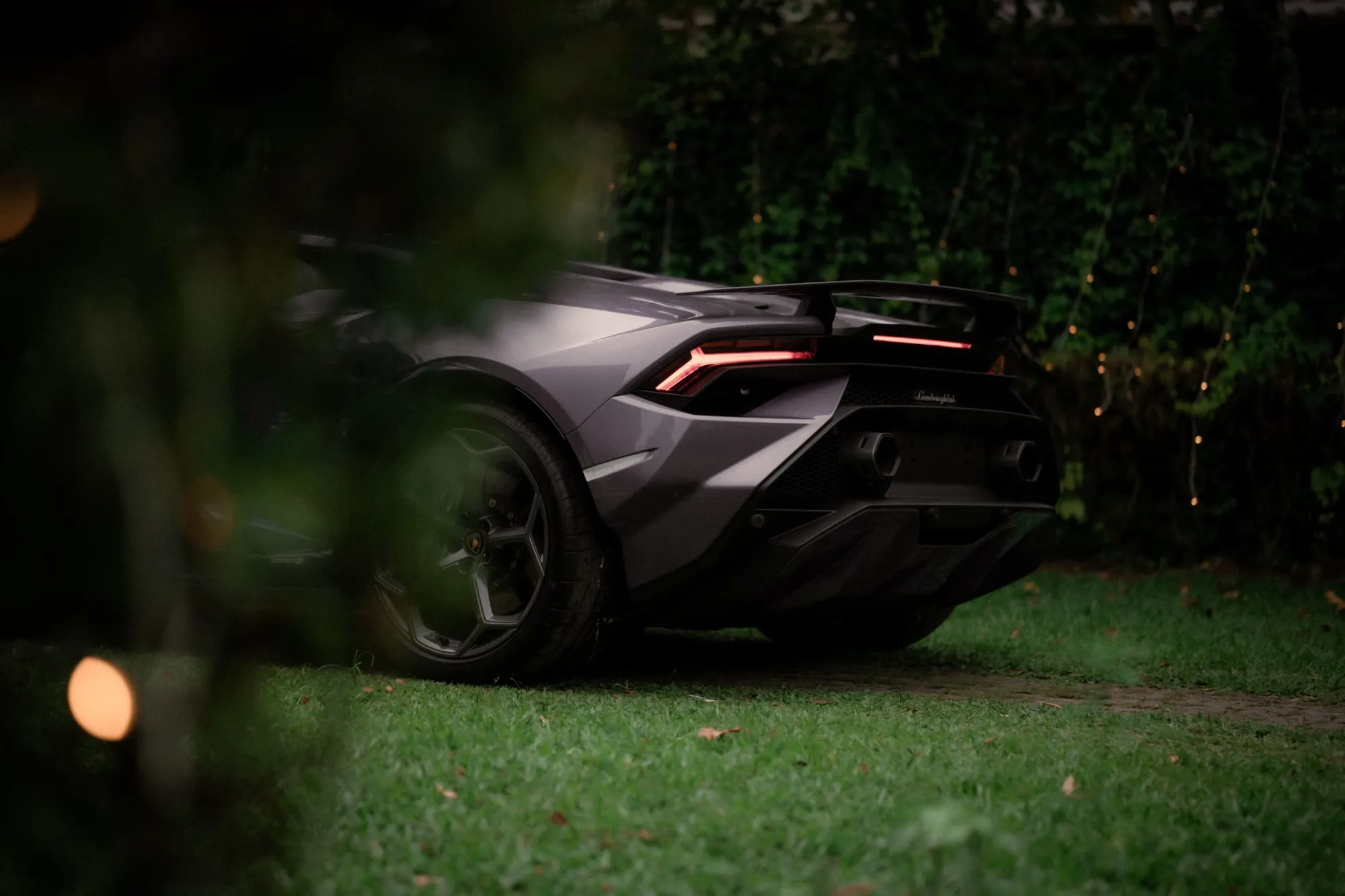 Grey supercar parked on grass at night