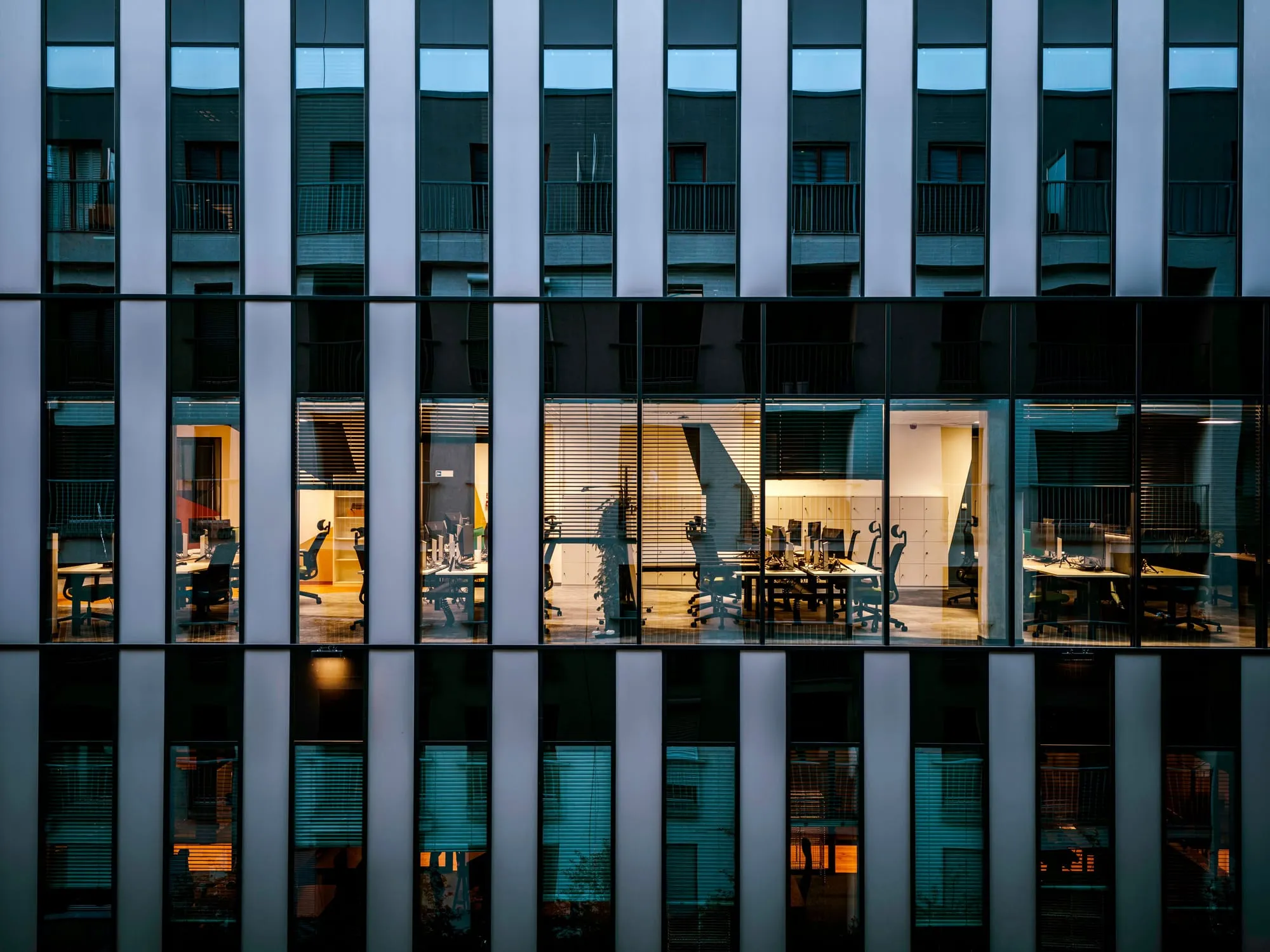 Office tower facade at dusk with lit windows