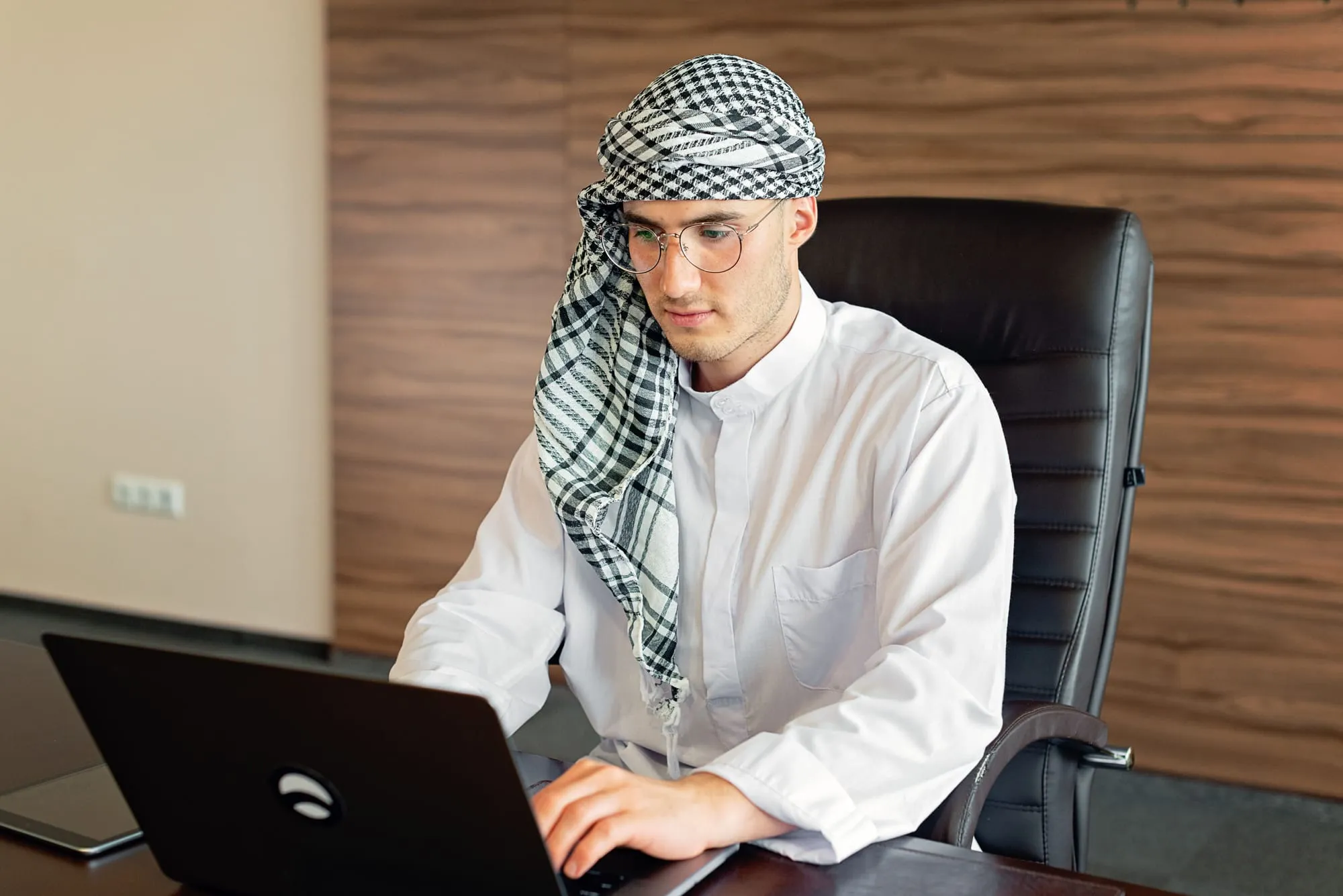 Portrait of a partner in traditional Emirati dress at his desk